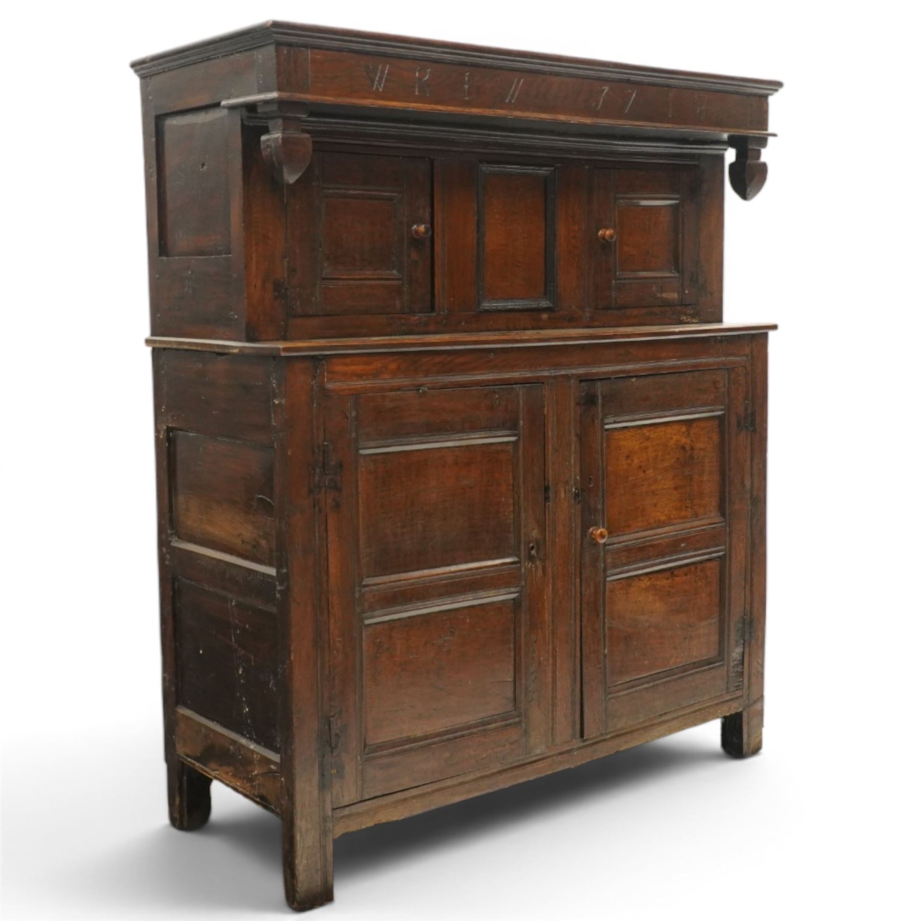 Early 18th century oak court cupboard, the projecting cornice carved with initials 'WKIW' and dated 1718 with turned terminals, fitted with two recessed panelled cupboard doors, large cupboard to base, raised on stile supports