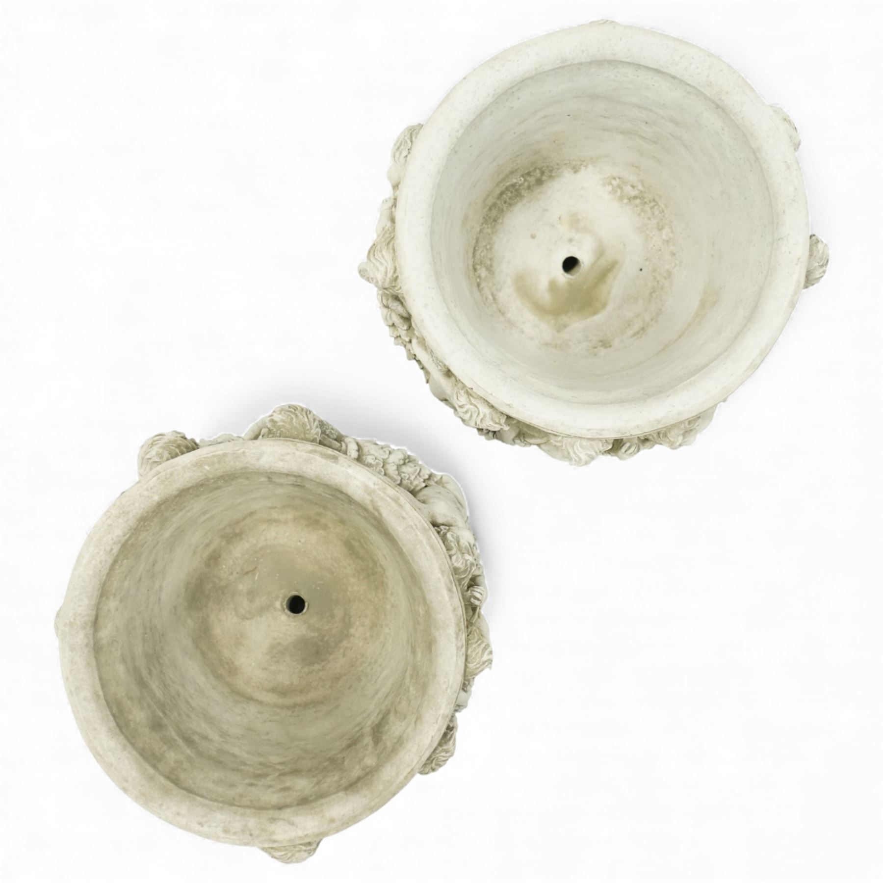 Pair of modern cast stone garden planters, circular tapering bodies moulded with cherubs in high relief among foliage and fruiting vines, in a weathered stone finish