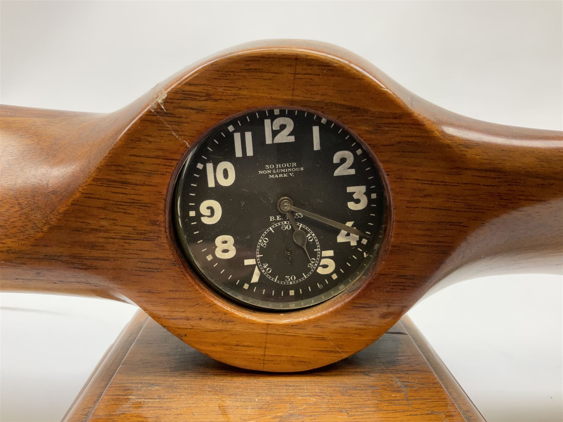 Early 20th century novelty small propeller mantle clock reputedly made by an apprentice at Blackburn Aircraft Works, Beverley & Hull in 1914, the mahogany case loosely inset with a WW1 DOXA Royal Flying Corps pocket watch, the black dial inscribed ' 30-Hour Non-Luminous Mark V.' number BE11653 with subsidiary seconds dial, the back marked with a capital 'A' above a broad arrow, mounted on a stepped square base L67cm