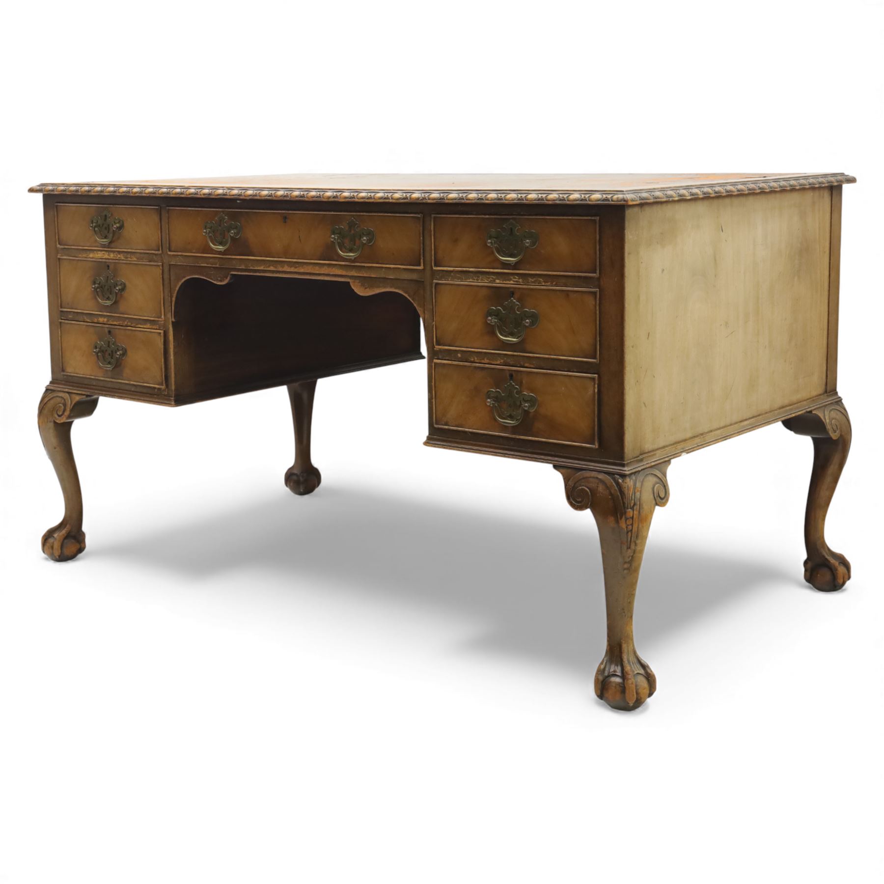 Waring & Gillow - Early 20th century mahogany desk, the leather-inset top above a shaped kneehole, central compartmented frieze drawer flanked by twin banks of of three drawers, each with brass handles, raised on cabriole legs with carved ball and claw feet (Height from floor to underside 62cm)