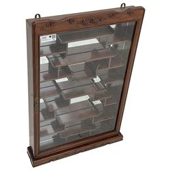 Chinese hardwood wall hanging curio cabinet, the mirror interior fitted with stepped shelves, enclosed by single glazed doors, decorated with carved scrolling foliage 