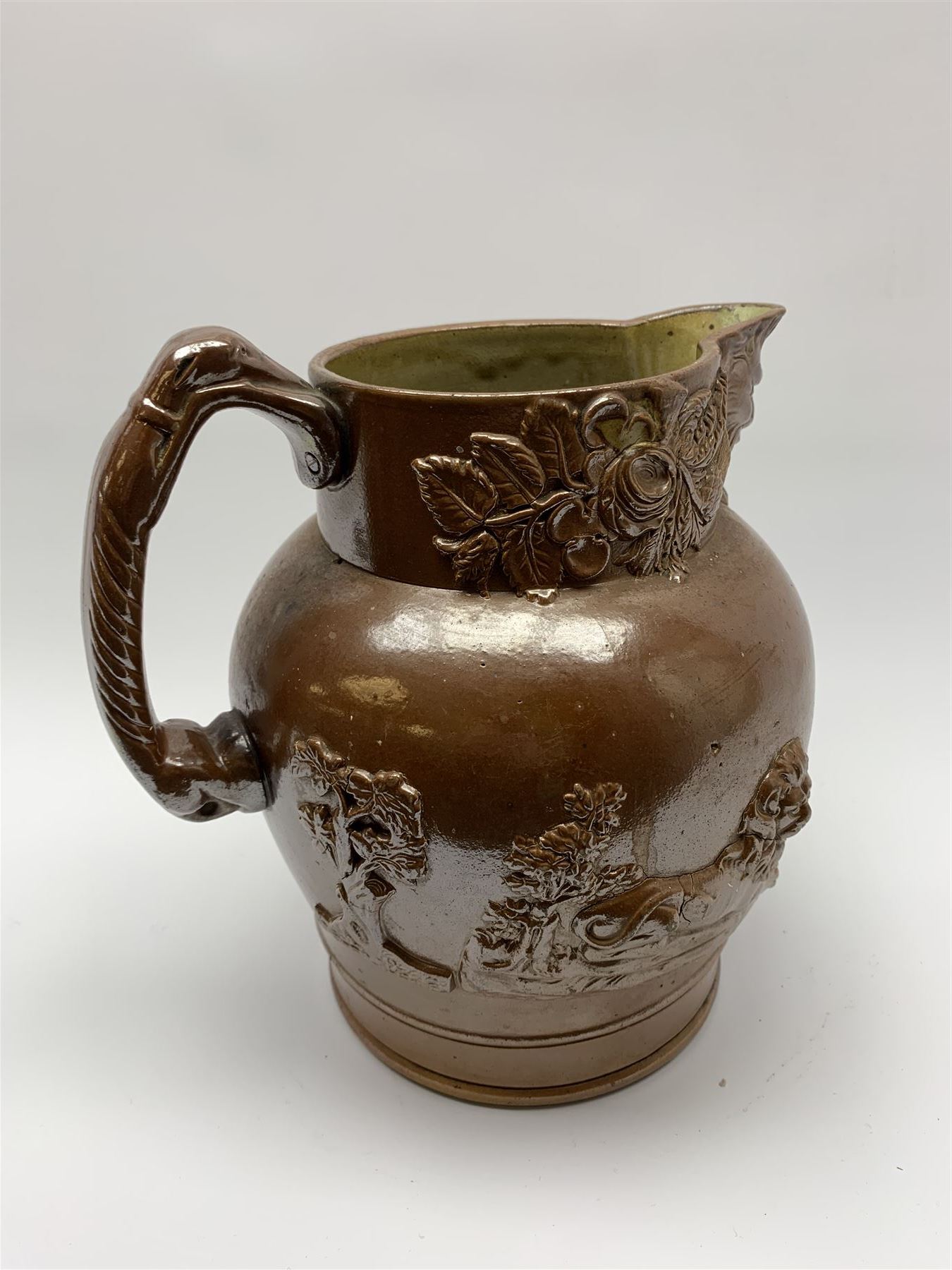 19th century salt glazed stoneware jug, with mask spout and greyhound modelled handle, the body decorated in relief with Royal Coat of Arms flanked by lions, the rim with the flowers of the union, roses, thistles and shamrocks, H26.5cm