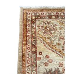 Pakistani ivory ground carpet, the field decorated with leaf branches, lotus flowers and roses, wide guarded border long leaves and stylised plant motifs