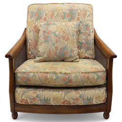 Ercol – bergère four piece suite, including armchair, two seat sofa, three seat sofa and footstool, all with removable floral upholstered cushions, the frames with side caning and rounded arm supports in stained beech

Three seat (H 87cm, D 89cm, W 196cm)
Two seat (H 87cm, D 89cm, W 137cm)
Armchair (H 87cm, D 89cm, W 87cm)
Footstool (H 28cm, D 55cm, W 55cm)