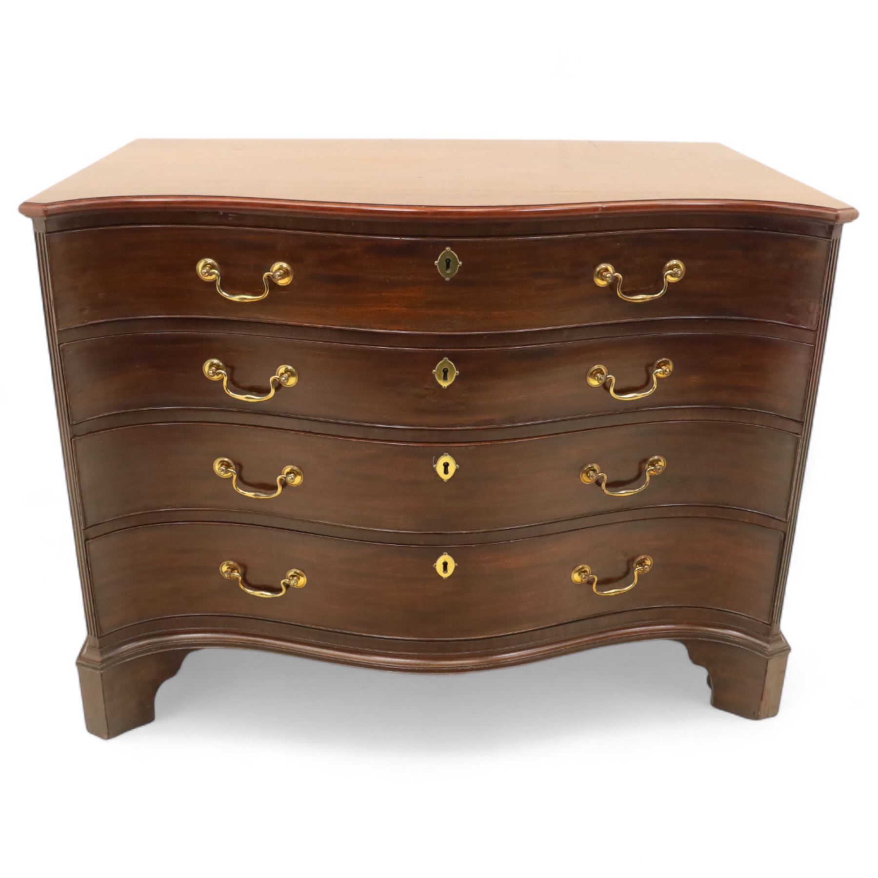 George III mahogany serpentine chest, moulded top over four cock-beaded drawers, the top drawer fitted with baize lined slide opening to reveal divisions,  enclosed by canted and fluted upright corners, the drawer fronts fitted with brass swan neck handles and circular plates with oval escutcheons, lower moulded edge over bracket feet, on lignum vitae castors