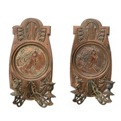 Pair of late 19th/early 20th century Art Nouveau copper twin branch wall sconces, each with shaped back plate chased with a central panel of a maiden in profile above and surmounted by foliate motifs, supporting two foliate open cast branches with bud sockets above conforming drip pans, H31cm W16cm D8.5cm
