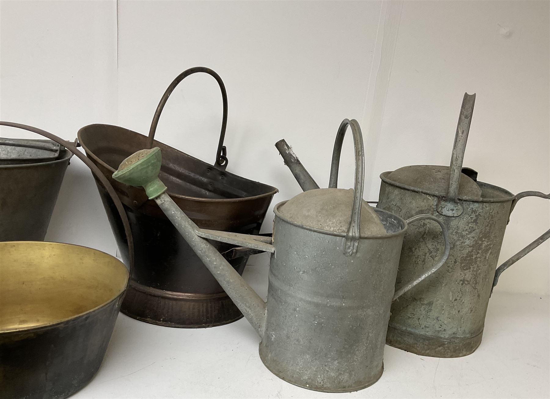 Two vintage galvanised watering cans, three galvanised buckets and a brass jam pan