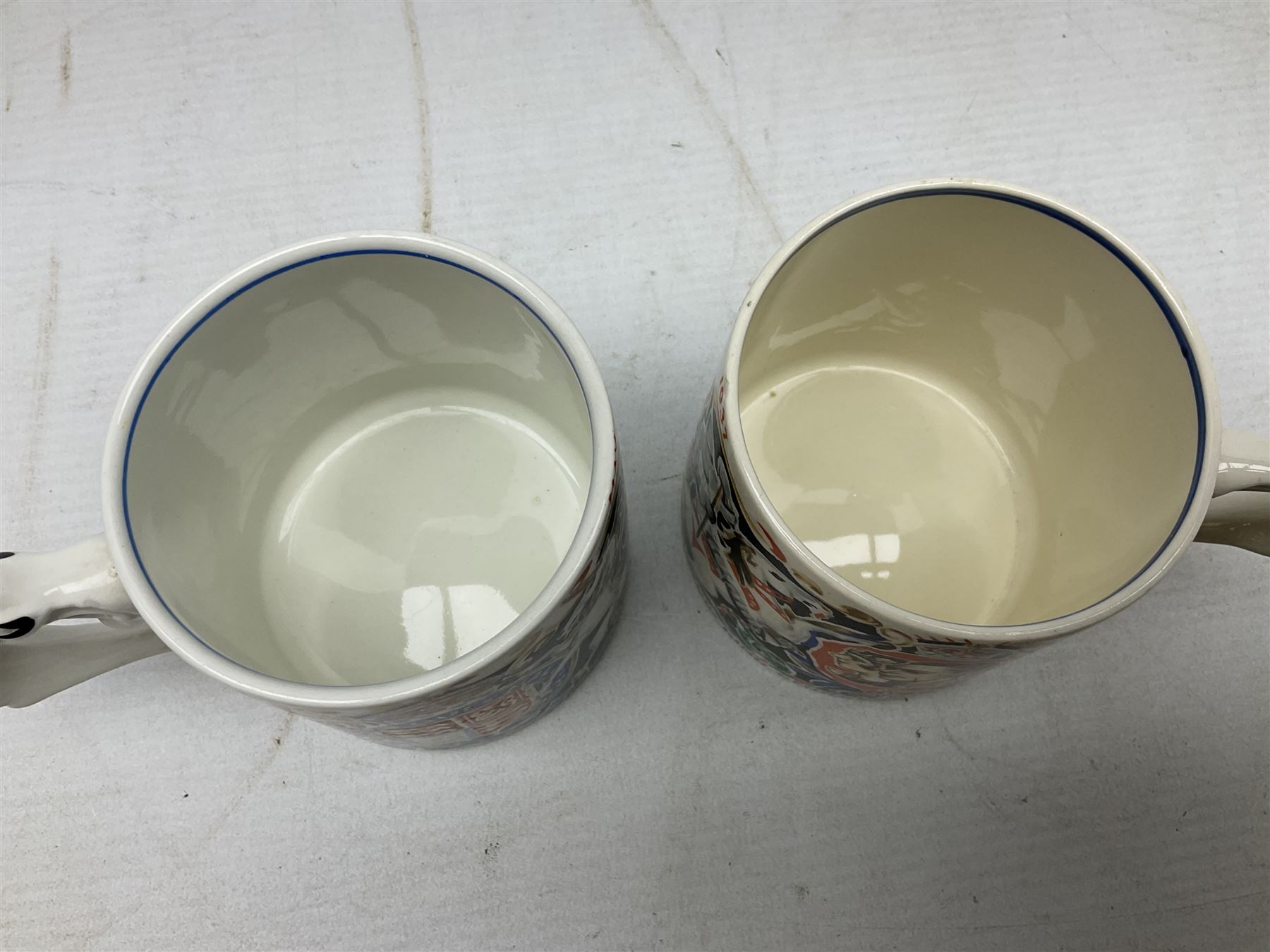 Two Dame Laura Knight coronation mugs for King George VI and Queen Elizabeth, comprising a Burleigh Ware example and a J&G Meakin example, each with a lion moulded handle and printed marks beneath, H8cm