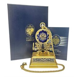  Franklin Mint House of Faberge 'The Imperial Collector Watch', the full hunter pocket watch with blue guilloche enamel and House of Faberge double eagle logo to gilded cover, opening to reveal a skeleton movement and enamel dial, upon a gilded stepped base supported by a pair of griffins, with a gilded watch chain, in original box with certificate of authenticity, including stand H14cm