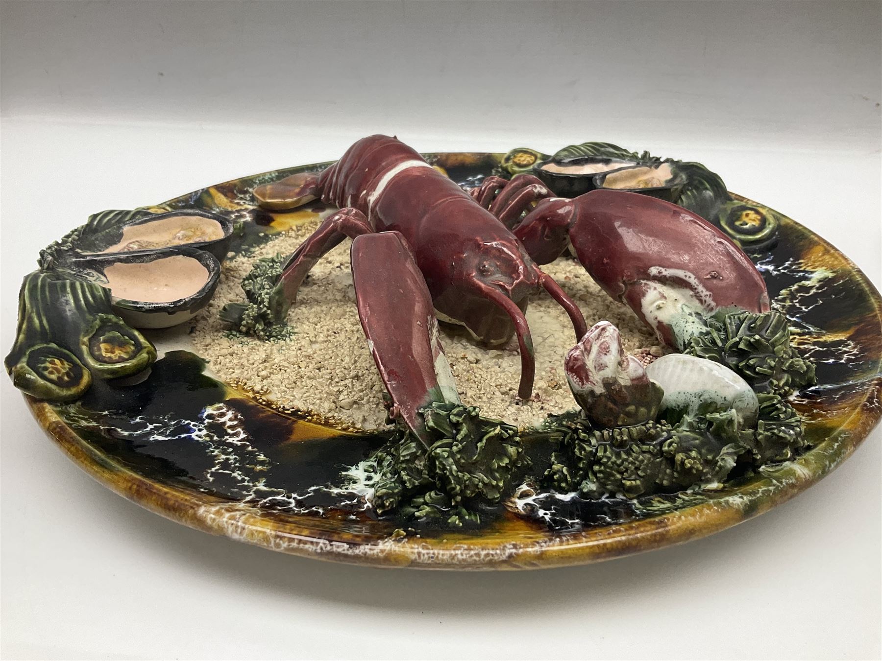 Two 20th Century Portuguese Palissy style Majolica wall plates, one depicting a crab, the other a lobster each to the centre modelled in relief surrounded by encrustations and shells, both with impress marks beneath, D32cm
