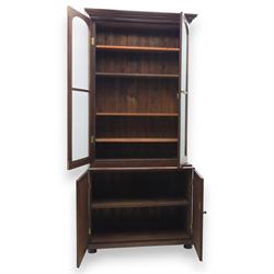 20th century mahogany display bookcase, projecting moulded cornice over a pair of glazed doors with shaped upper glazing and plain lower panes, opening to reveal shelved interior, the base with two recessed panel cupboard doors, raised on a moulded plinth with compressed bun feet