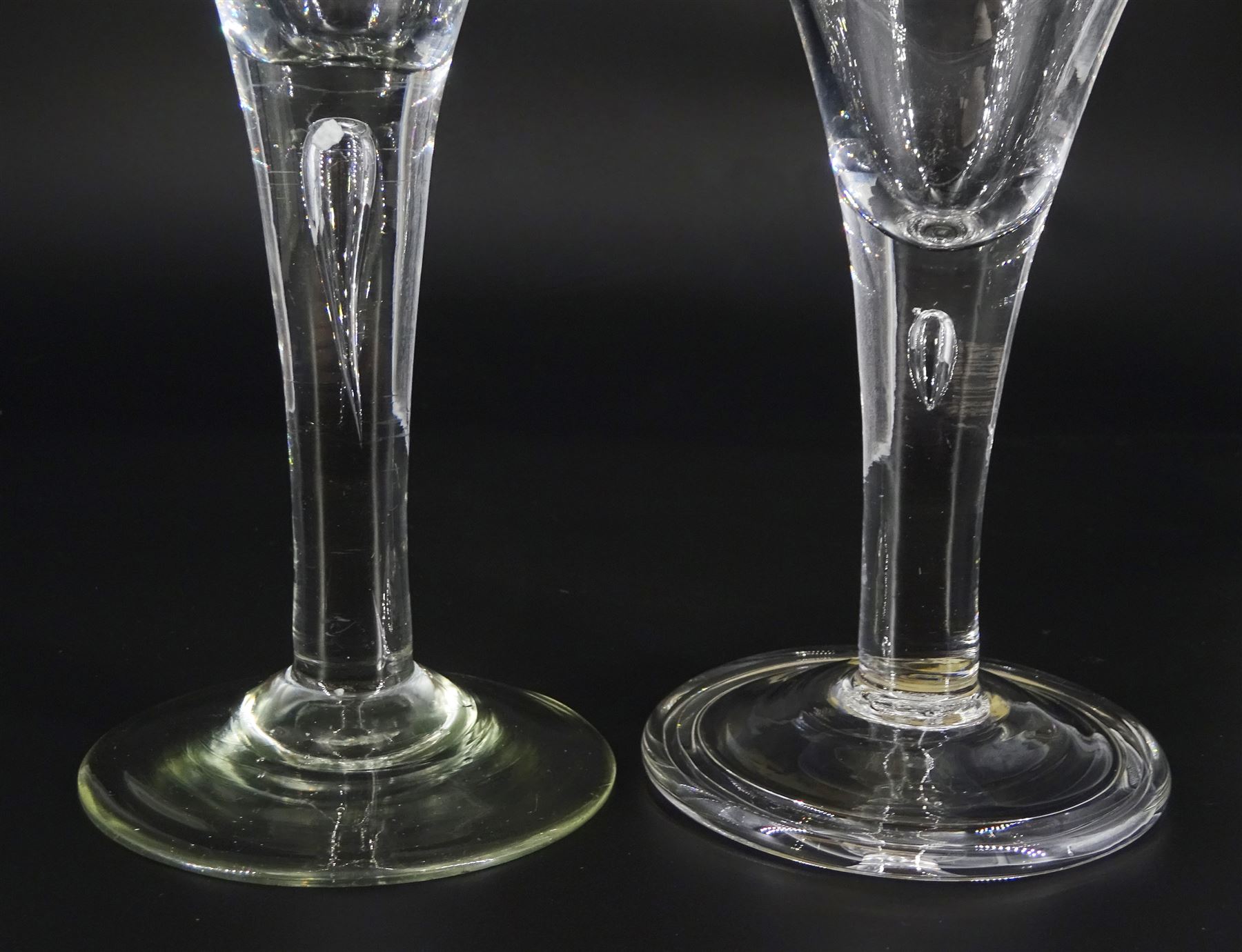 Two 18th century drinking glasses, the drawn trumpet bowls upon stems with internal tears, one elongated, and conical feet, one folded, largest H16cm