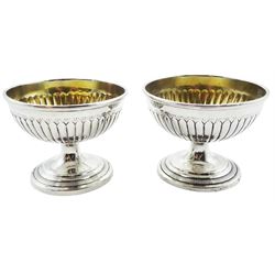 Two Georgian silver open salts, each with part fluted bowl with gilt interior, upon circular stepped pedestal base, hallmarks worn and indistinct, H5.5cm D7cm, approximate weight 3.68 ozt (114.5 grams)