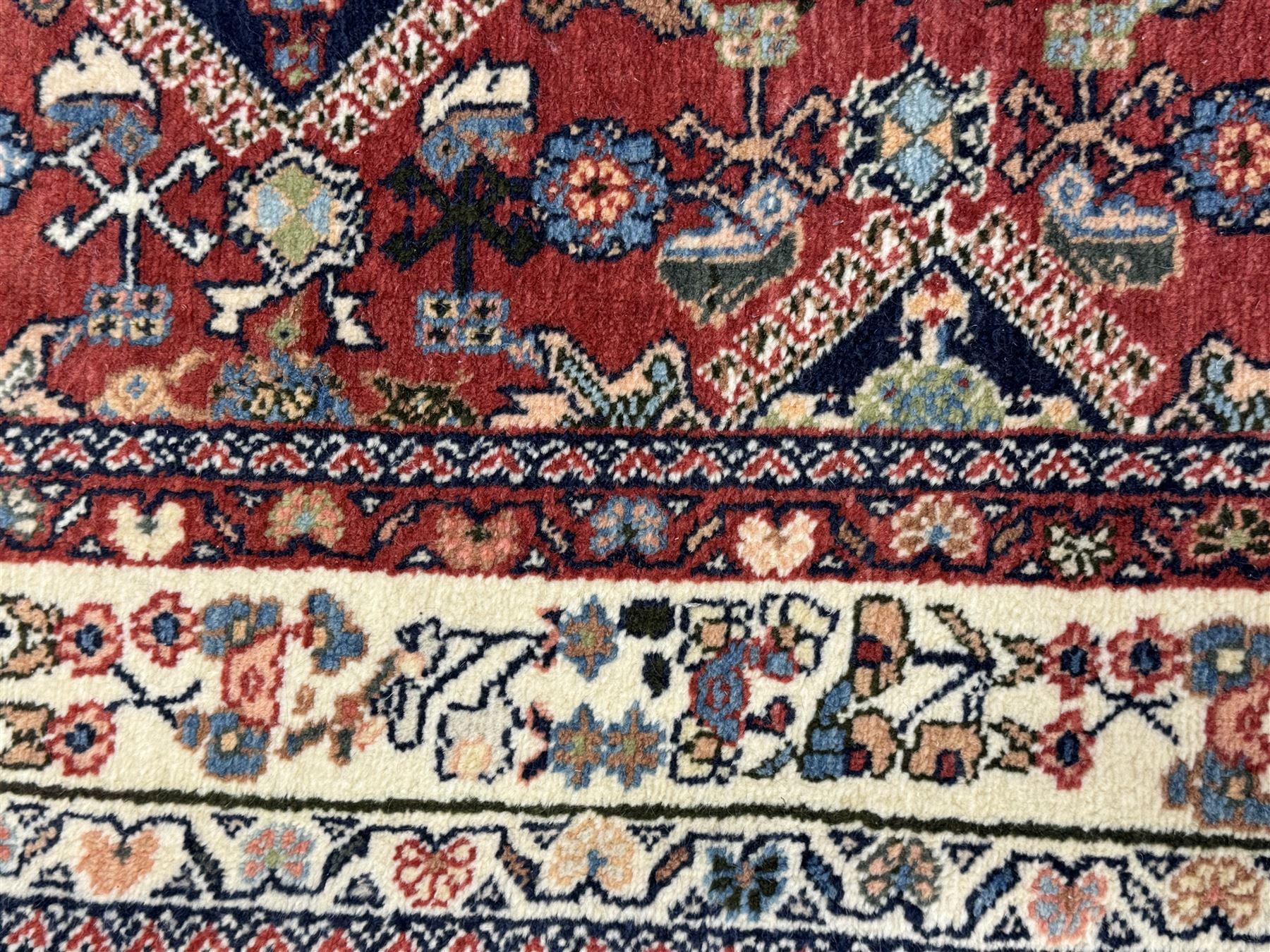 Pair of rugs one Persian hamadan rug central stepped medallion enclosing geometric motifs in ivory and brown, framed by a cream border with scrolling palmettes and fringed ends (H 156cm W 105cm), one Pakistani Bokhara rug rust red ground with repeated Tekke gul motifs within rosette and lozenged borders, fringed ends (H 98cm, W 65cm)