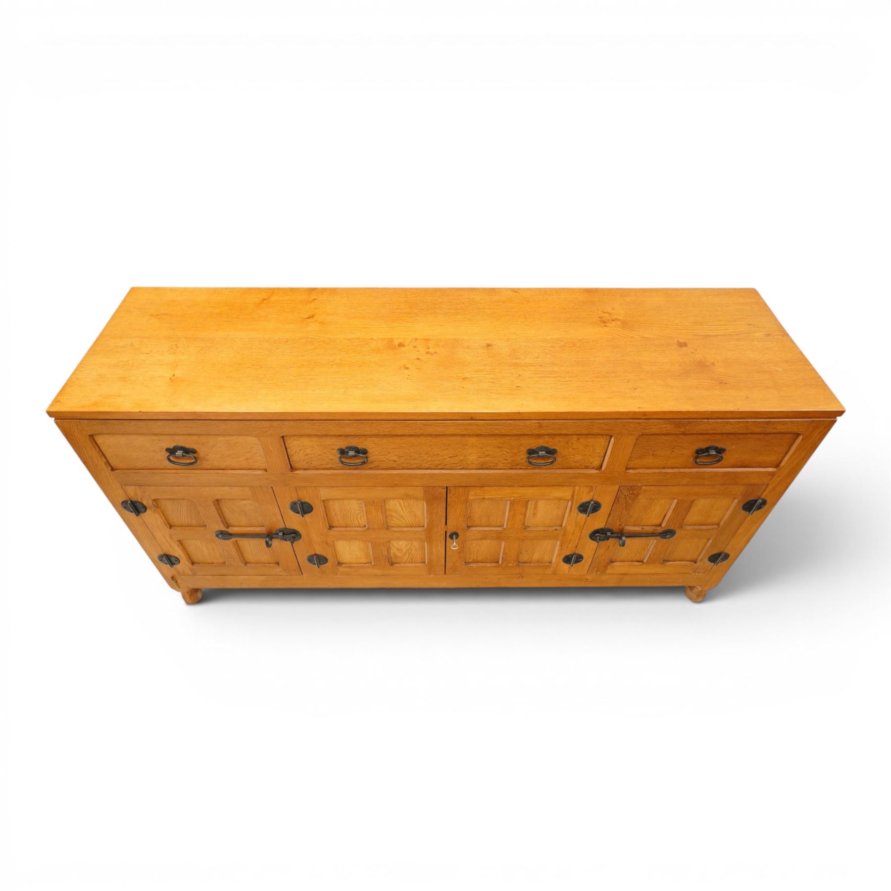 Lizardman - oak 5' sideboard, rectangular top over three panelled frieze drawers, fitted with two double panelled cupboards with wrought iron handles and locks, raised on tapered octagonal feet, with carved lizard signature, by Derek Slater of Crayke