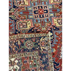 Persian Heriz carpet, the red ground field decorated with geometric star medallion surrounded by interlaced foliate and stylised plant motifs, repeating guarded border decorated with flower heads