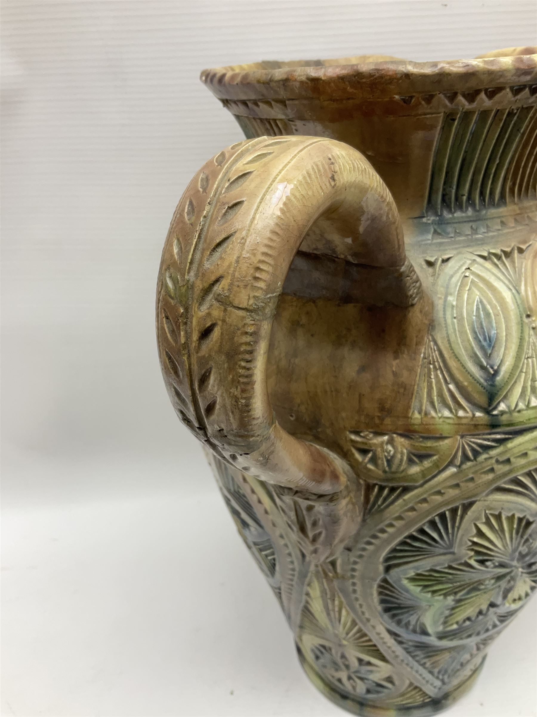 Early 20th century Royal Doulton stoneware vase, decorated with a stylized floral design below a wavy rim, monogrammed B.N, possibly for Bessie Newbery, H28cm, together with an early 20th century glazed jug, heavily carved throughout (2)