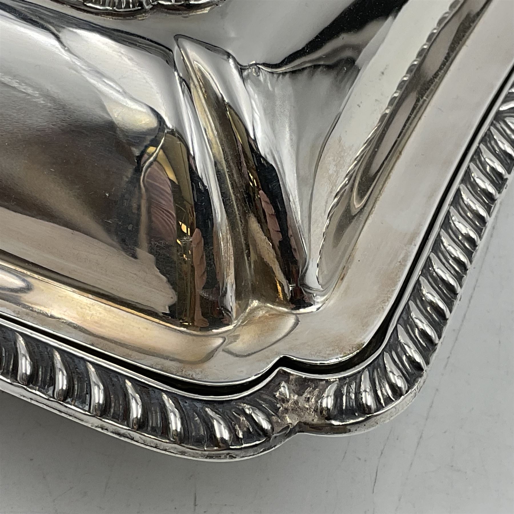 Early 20th century silver entree dish and cover, of rectangular form with shaped corners and oblique gadrooned borders to base and cover, the cover with loop 'bamboo' handle, hallmarked Thomas Bradbury & Sons Ltd, Sheffield 1930, including handle H10.5cm L24.5cm