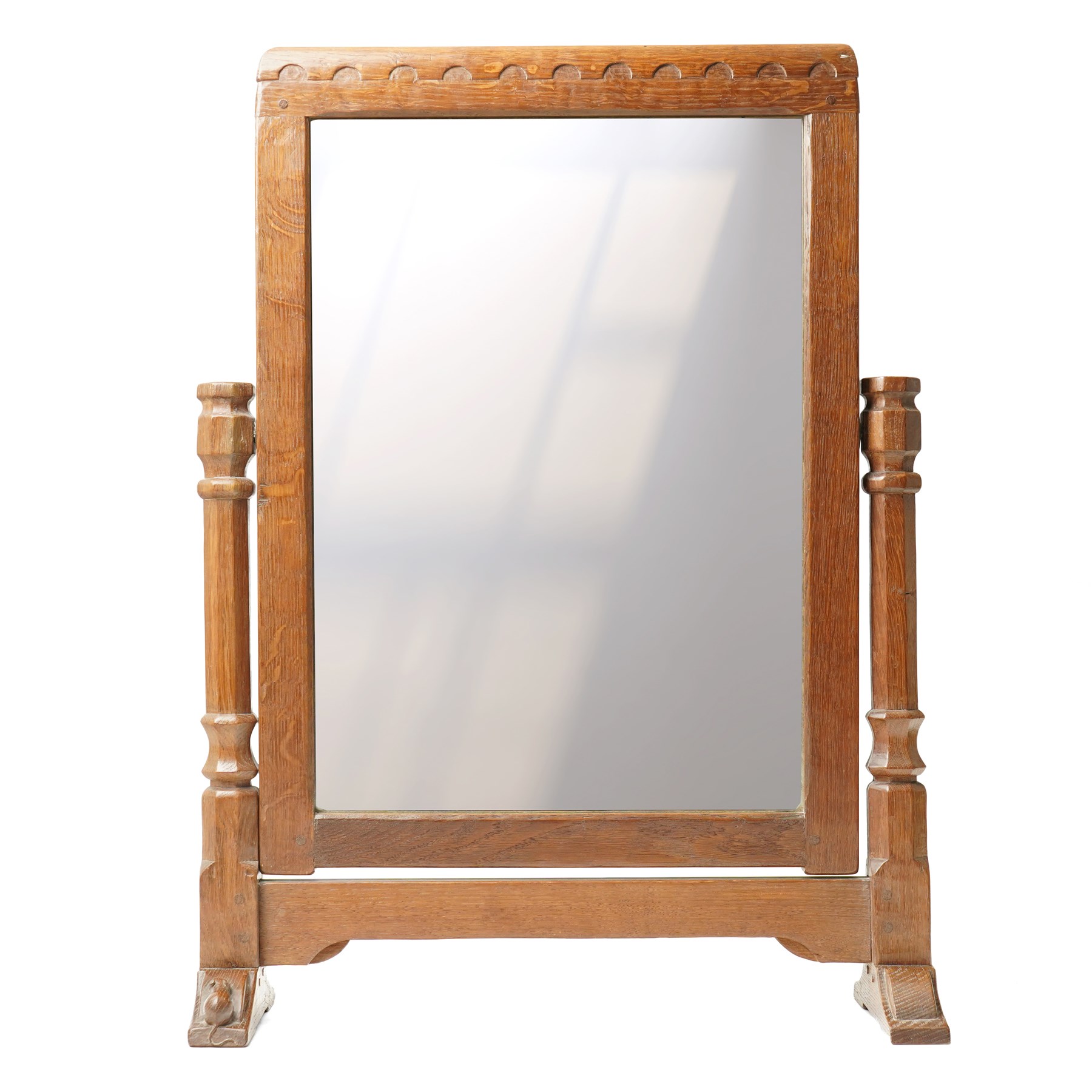 Mouseman - 1930s/40s lightly adzed dark oak dressing table swing mirror, the arcade carved cresting rail over a rectangular plate, the mirror pivots between two lappet-carved turned octagonal supports with dished tops, raised on sledge feet, with carved mouse signature, by the workshop of Robert Thompson of Kilburn