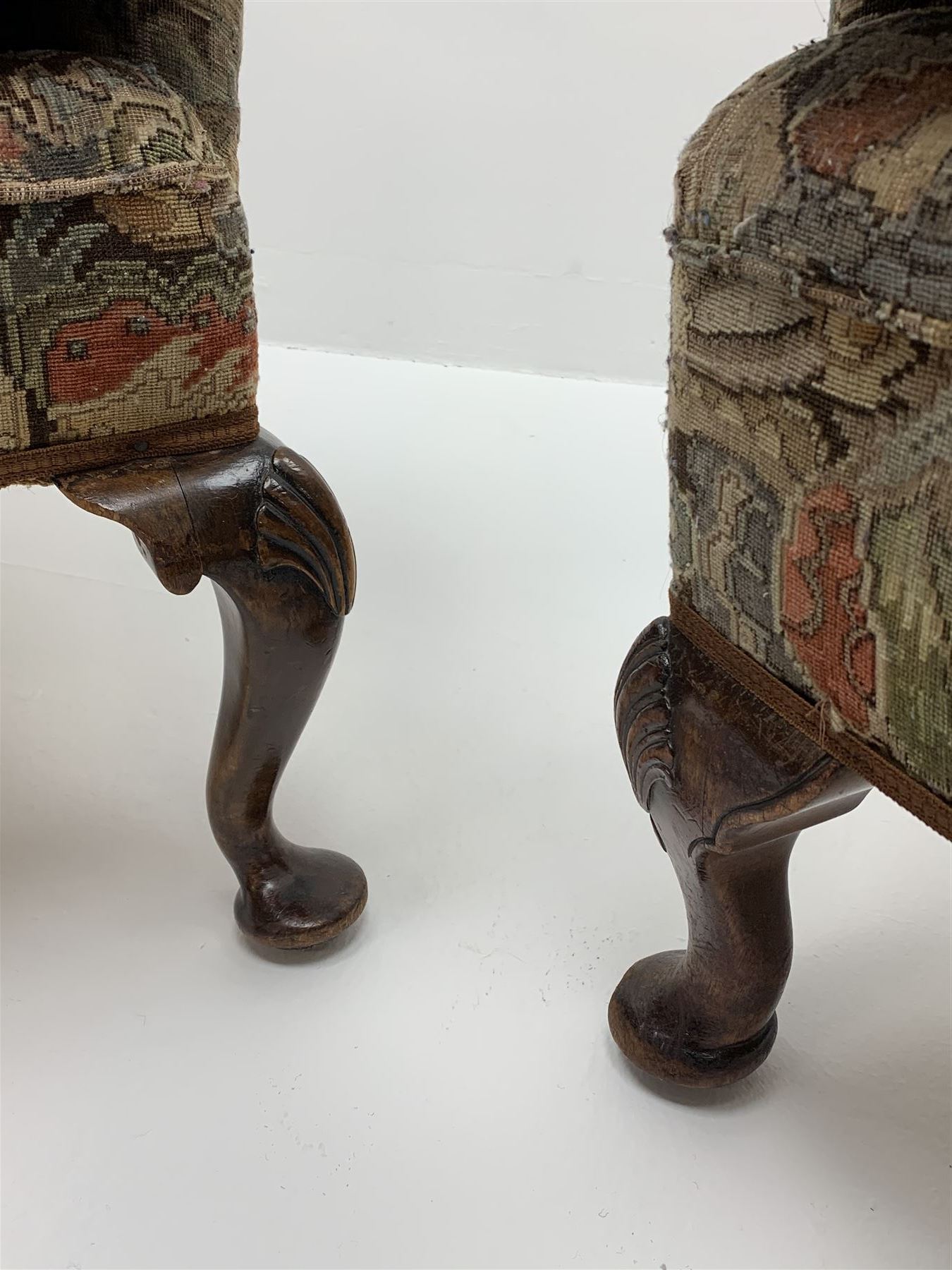 Matched pair early 20th century Queen Anne style wingback armchairs, walnut framed, sprung seats with seat cushions upholstered in needle work cover, shell carved cabriole front feet