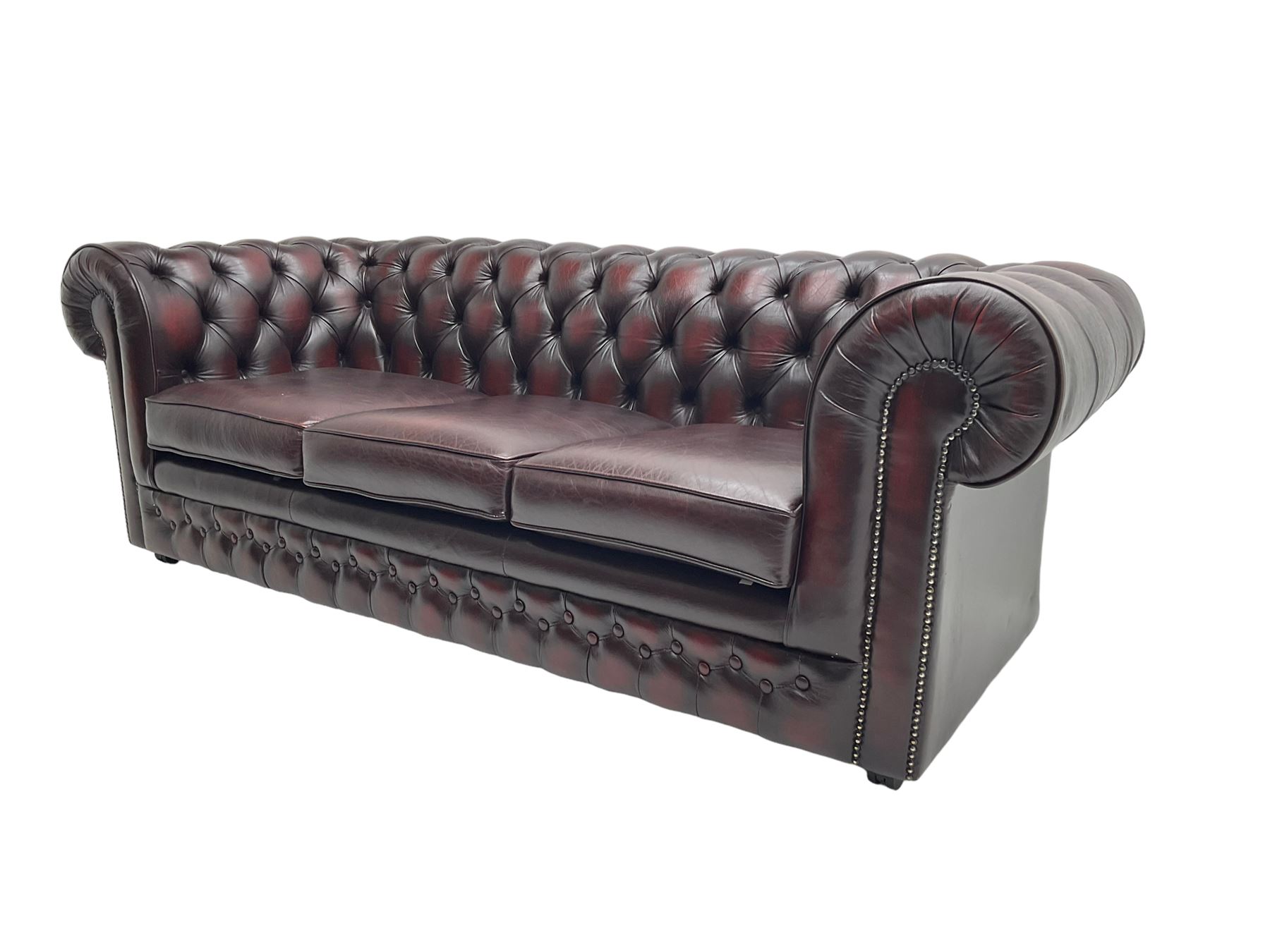 Thomas Lloyd - three seat Chesterfield sofa, upholstered in buttoned oxblood leather, on castors 