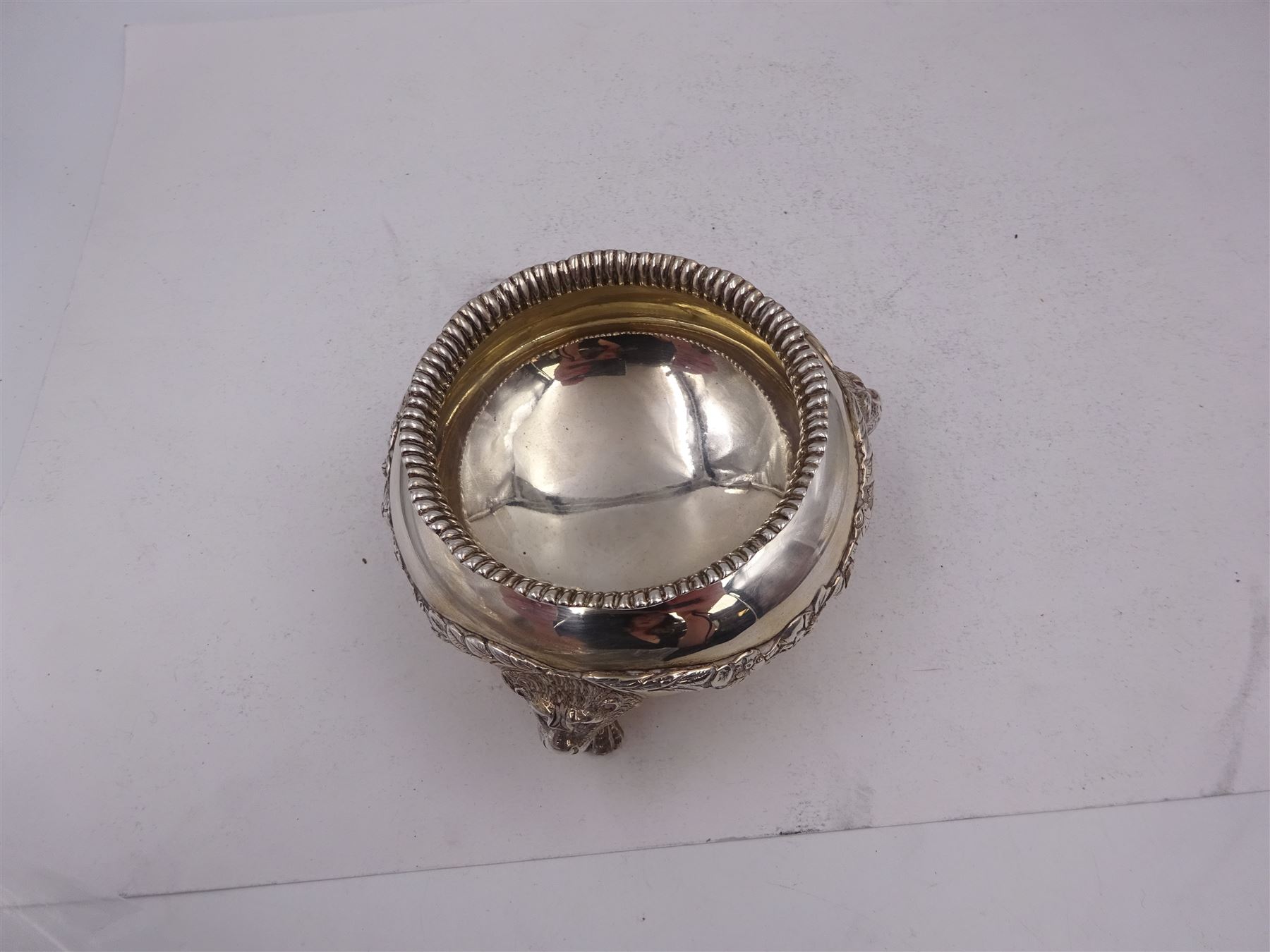 Early 20th century silver open sucrier, of circular form, with fluted gadrooned rim and decorated in relief with floral swags, united by three lion mask mounts and upon three paw feet, hallmarked Z Barraclough & Sons, London 1912, H6cm, D11cm, with similar spoon with lion mask finial, hallmarked London 1912, maker's mark indistinct