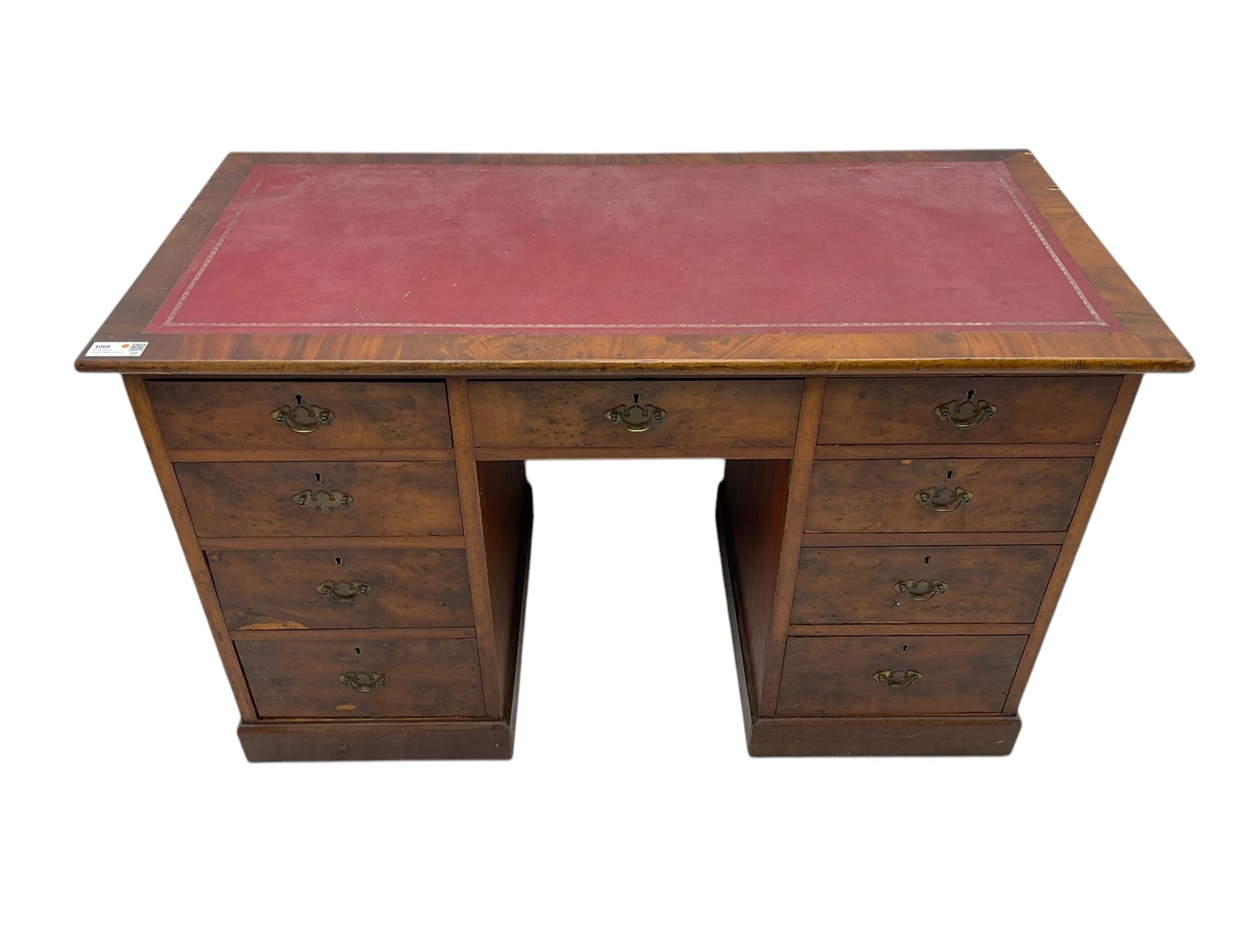 Late 19th to early 20th century walnut pedestal desk, rectangular top inset with red tooled leather writing surface, over a central frieze drawer flanked by two pedestals, each fitted with four graduated drawers with brass escutcheons and drop handles, the whole raised on a plinth base