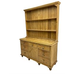 Victorian pine dresser base, fitted with seven drawers with turned handles, flanking central panelled cupboard, with two-tier plate rack