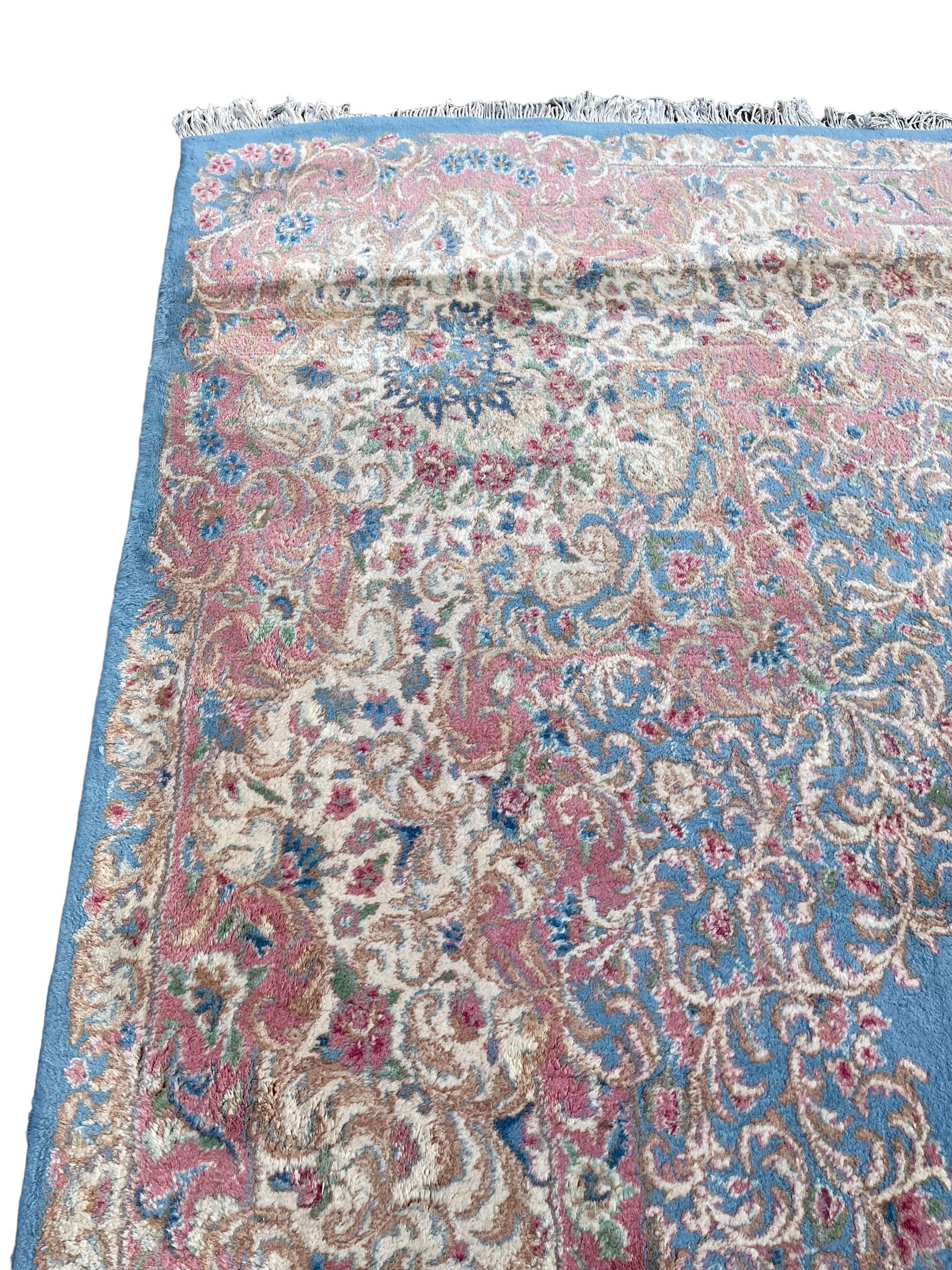 Large Persian design carpet, plain light blue field with floral design central medallion, scrolling foliate spandrels and borders decorated with flower heads