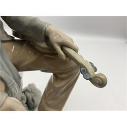 Lladro figure, Violinist, modelled as a man seated upon a  mile stone holding a violin, sculpted by Salvador Furió, no 4887,  year issued 1984, year retired 1981, H35cm