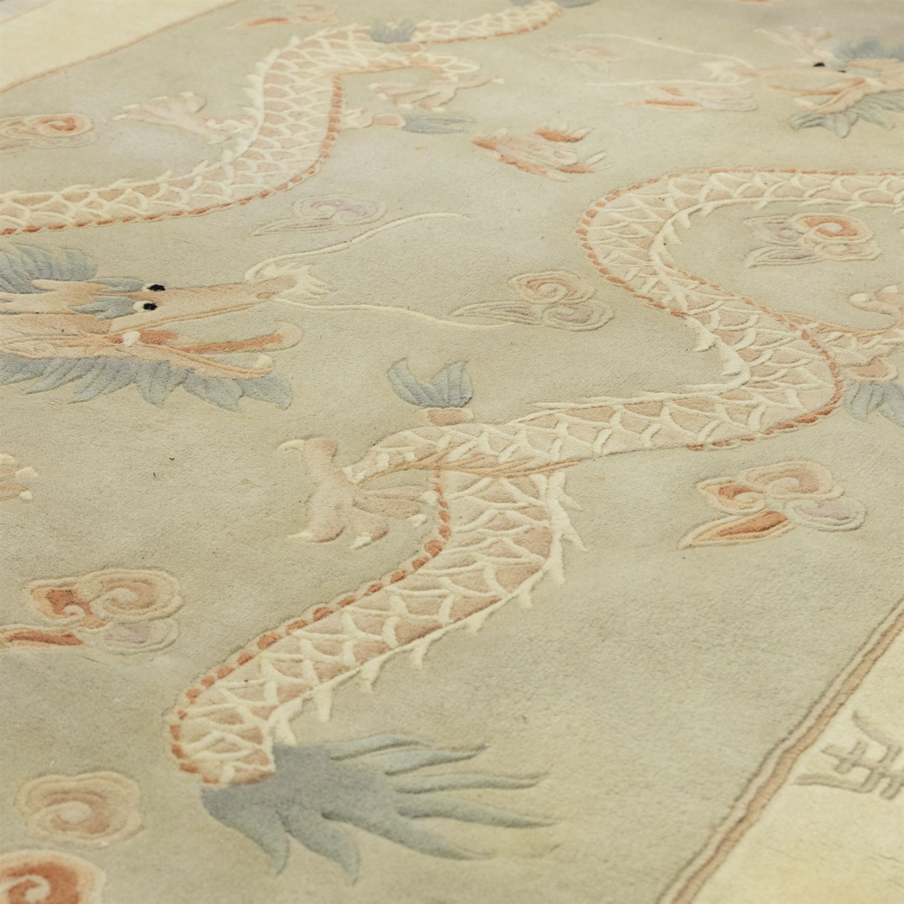 Chinese wool rug, the pale grey central field decorated with two stylised dragons, flaming pearls and cloud scrolls, within a cream border of shou medallions and geometric motifs, with cotton fringe ends