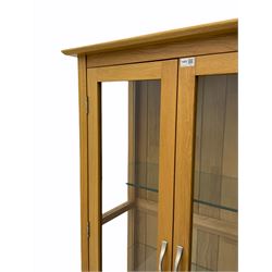 Light oak display cabinet, enclosed by two glazed doors, two drawers