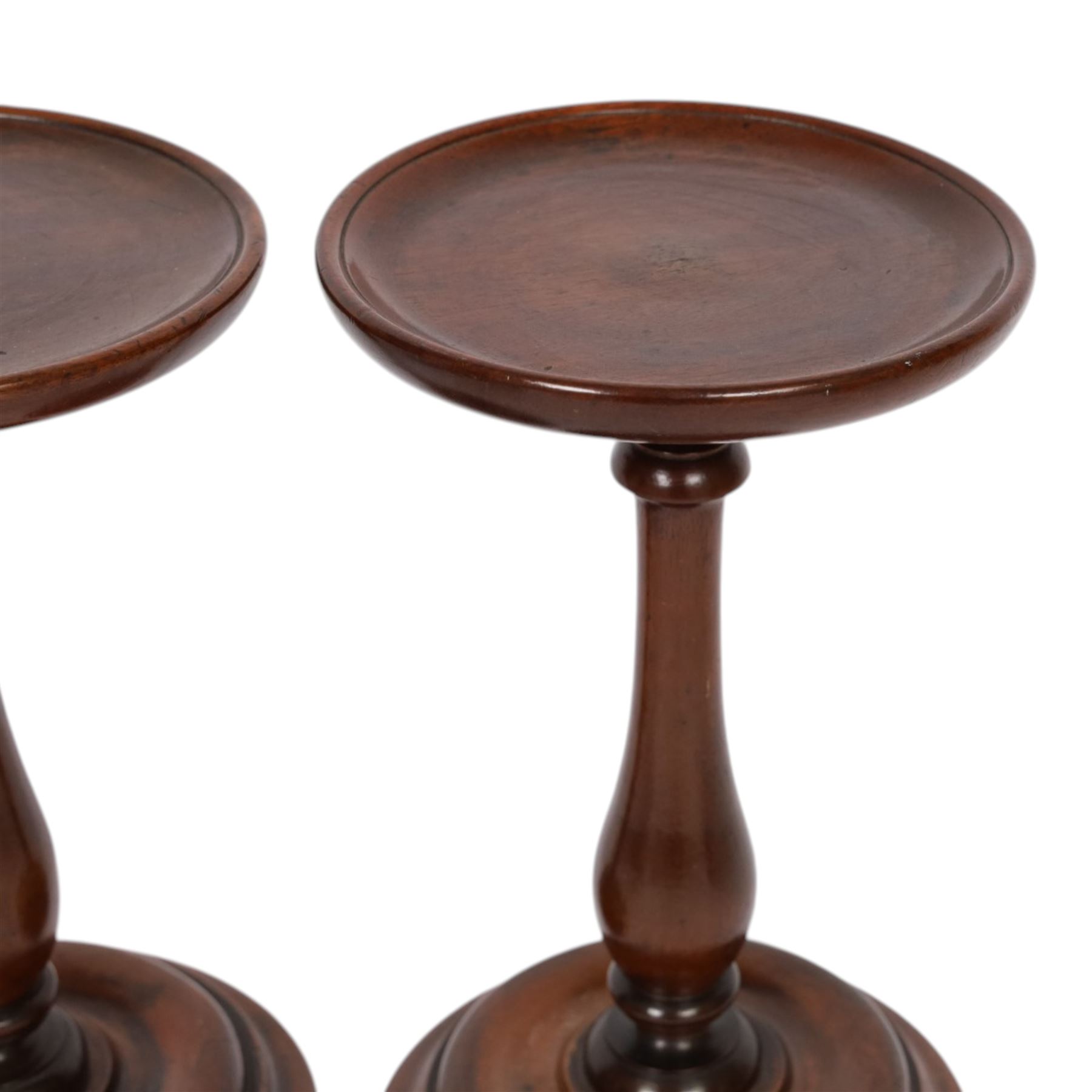Pair of 19th century turned mahogany candle stands, each with circular top upon a baluster stem and circular stepped base, H25.5cm