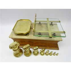  Set of 19th century oak counter top shop balance scales, marble top, openwork brass frame plate with glass insert, L52cm and a graduated set of brass bell weights 7lbs to 4oz   