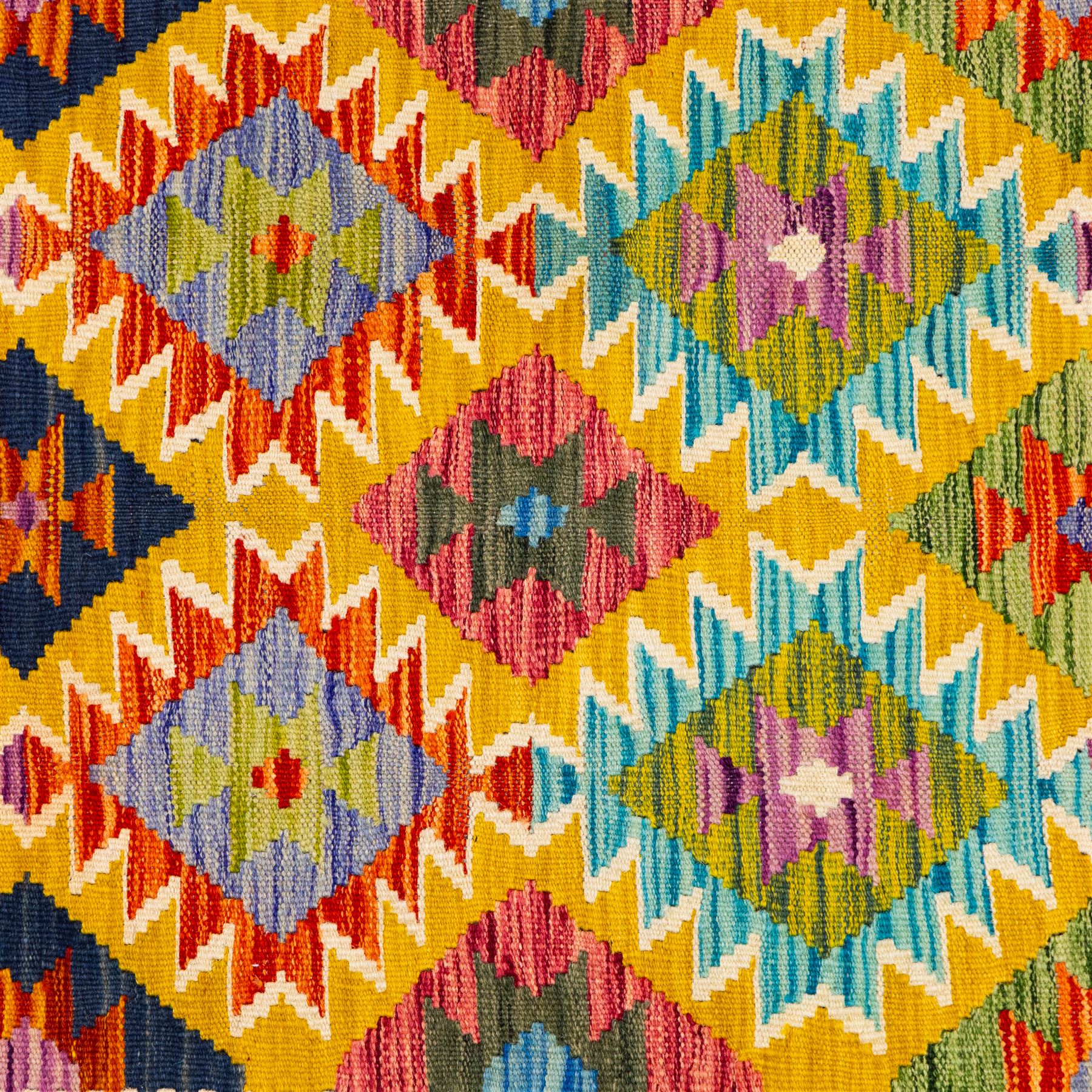 Afghan Chobi kilim flatweave runner with a repeating stepped diamond medallion design in live green, sky blue, rust, teal, purple, and ivory, framed by geometric borders in tones of orange and crimson