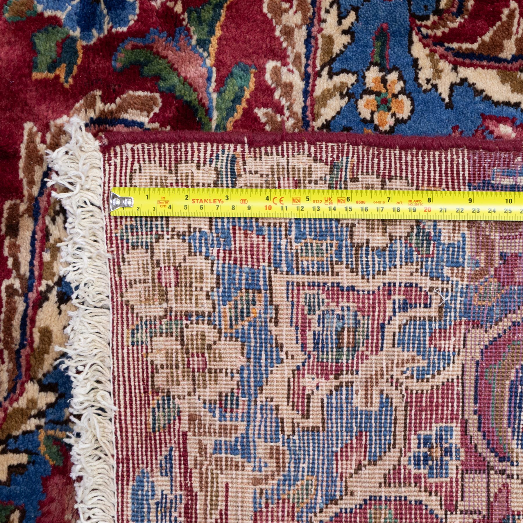 Large Central Persian Kirman hand-knotted carpet, raspberry red field, with central shaped medallion surrounded by an intricate arrangement of scrolling vines and floral sprays, within conforming spandrels and a pale blue border decorated with floral motifs, enclosed by guard stripes, with cotton fringe ends 