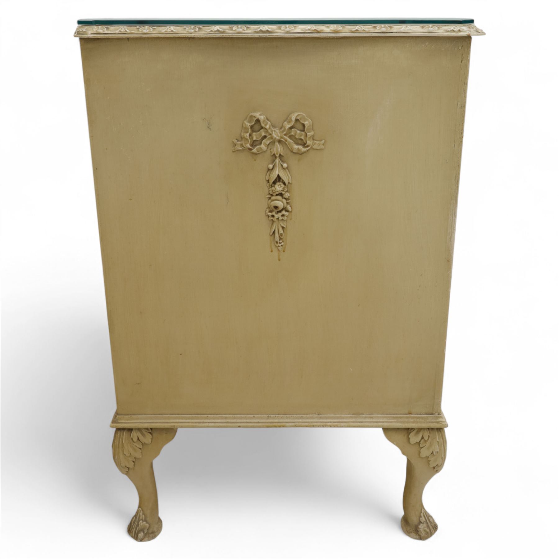 French design cream painted three drawer commode, shaped front with floral garland appliqués, fluted uprights and acanthus carved cabriole legs terminating in scroll feet