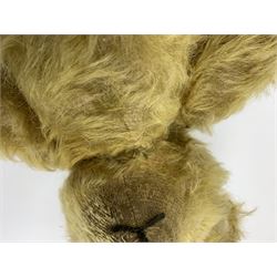 Early 20th century English teddy bear, WW1 period, with wood wool filled mohair body, fixed head with one boot button eye and vertically stitched nose and mouth and jointed limbs with cloth paw pads H16