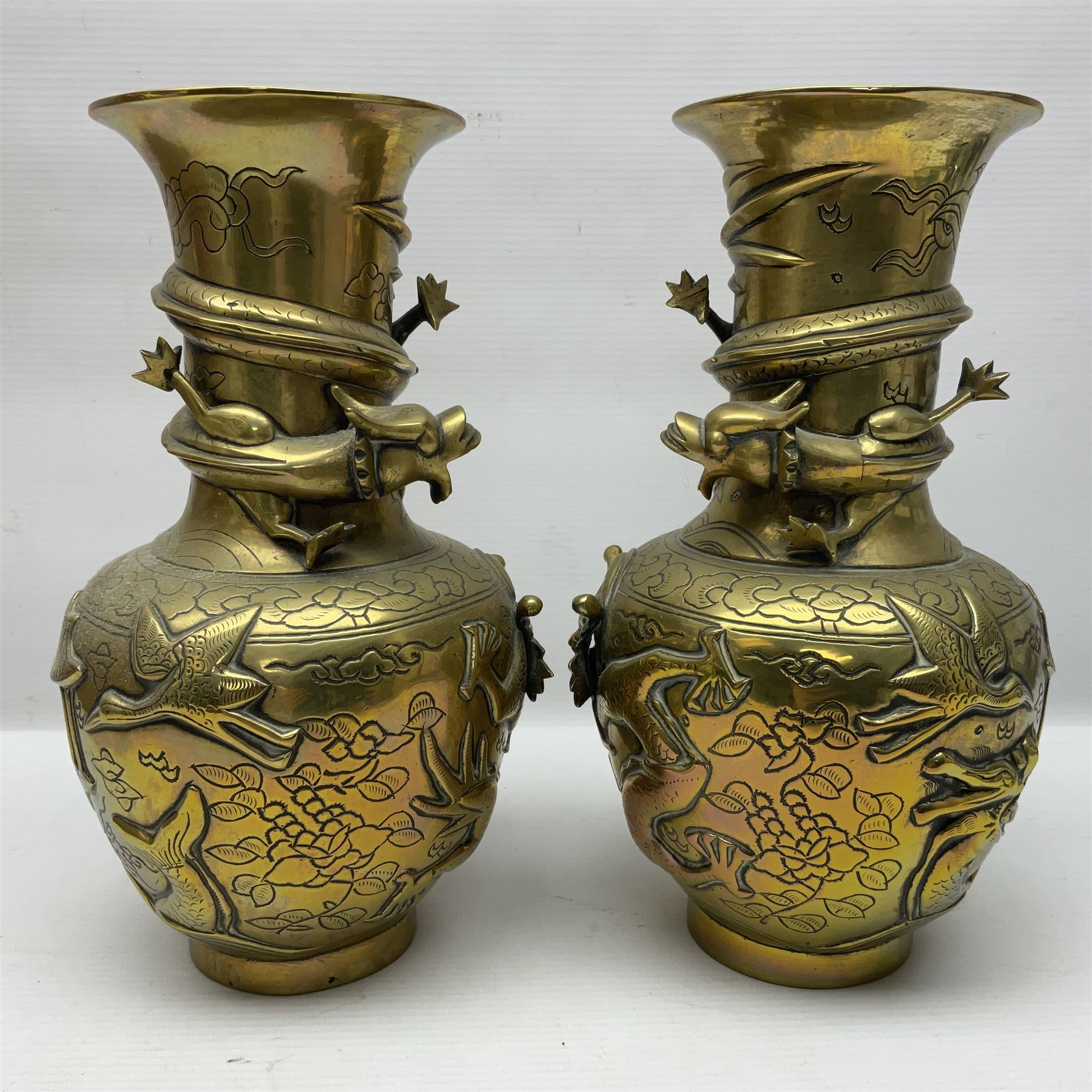 Pair of Chinese brass vases, of ovoid form with elongated neck and fluted rim, decorated in high relief with a dragon chasing a flaming pearl around the neck, the body with dragons, birds and buildings, with character marks beneath, H25cm