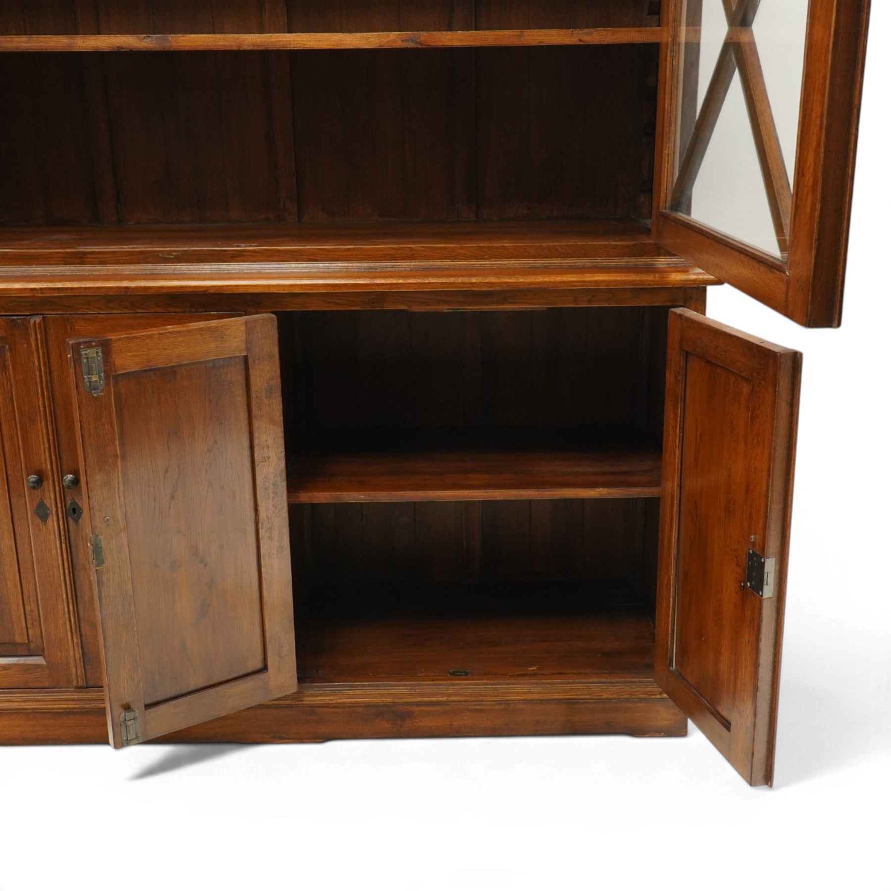 OKA - Glazed bookcase dark oark cabinet, the top with projecting cornice above astragal style glazed doors metal turned knobs, enclosing adjustable full length shelving, the lower half with two sets of twin cabinet doors housing fixed shelving, raised on a moulded plinth base  