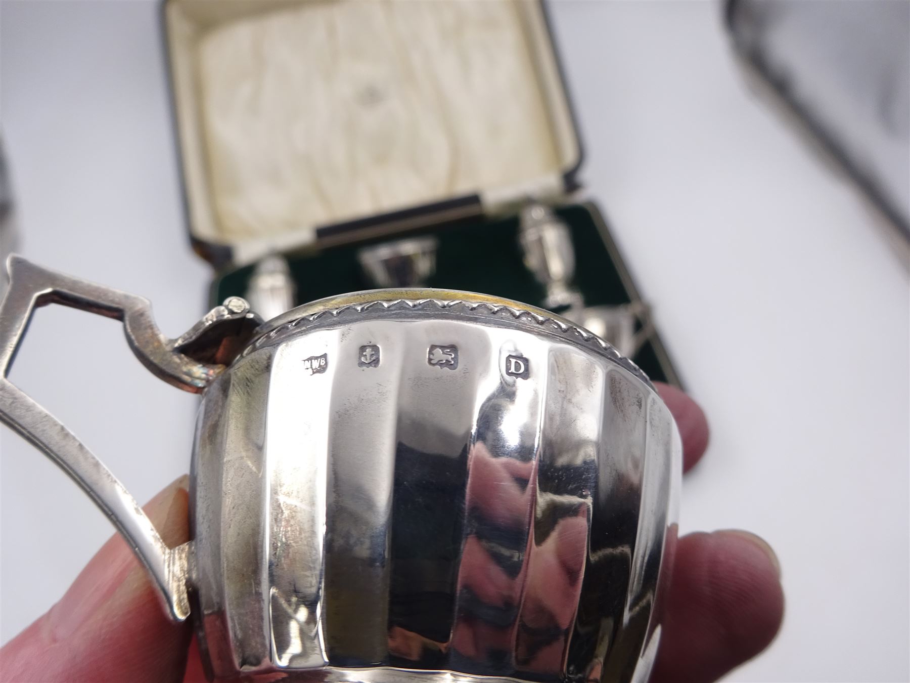 1920s silver six piece cruet set, comprising two mustard pots with covers, two open salts and two pepper pots, all of circular faceted form, mustards and salts with blue glass liners, hallmarked Mappin & Webb, Birmingham 1928, with four matched silver condiment spoons, hallmarked, contained within fitted case 