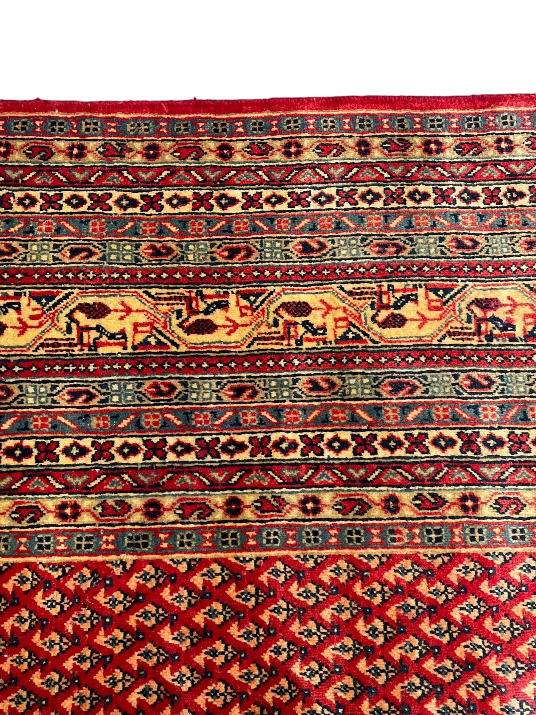 Persian Arak crimson ground carpet, the field decorated profusely with small repeating Boteh motifs, enclosed by multiple border bands decorated with repeating geometric and hook motifs