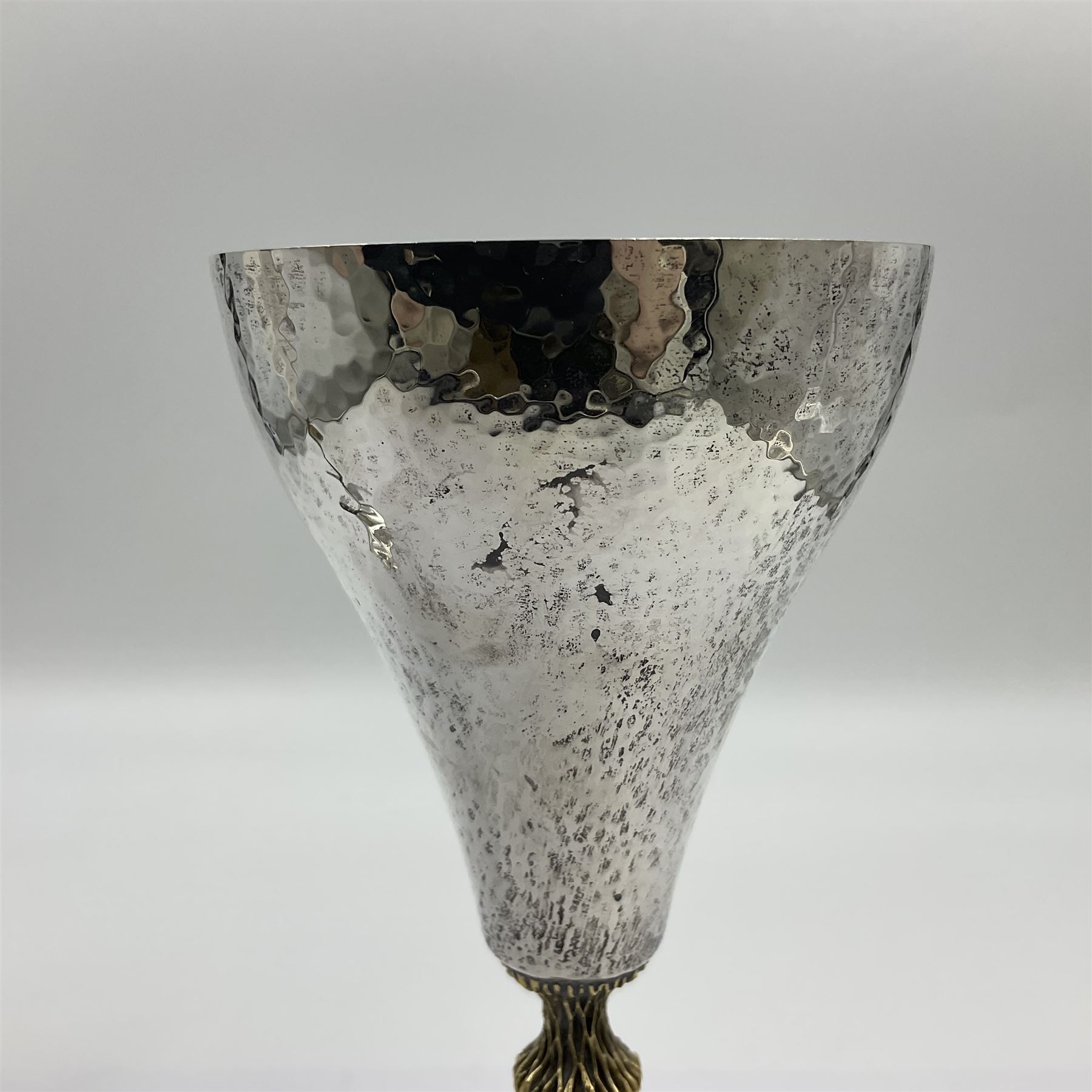 Pair of modern silver goblets by Stuart Devlin, the tapering cylindrical bowls each with spot hammered decoration and gilt interiors, the parcel gilt stems with signature textured detailing and six graduating knops, upon conforming spreading circular foot, hallmarked Stuart Devlin, London 1976, H17.7cm