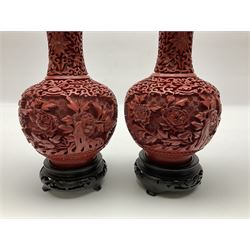 Pair of Chinese cinnabar lacquer vases, each of bulbous baluster form, carved with peonies and foo dogs amongst scrolls, with blue enamel interior and upon wooden bases, H20cm