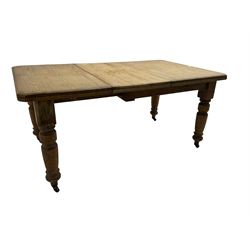 Late Victorian pine extending dining table, rectangular moulded top with canted corners and additional leaf, on turned supports with brass castors 