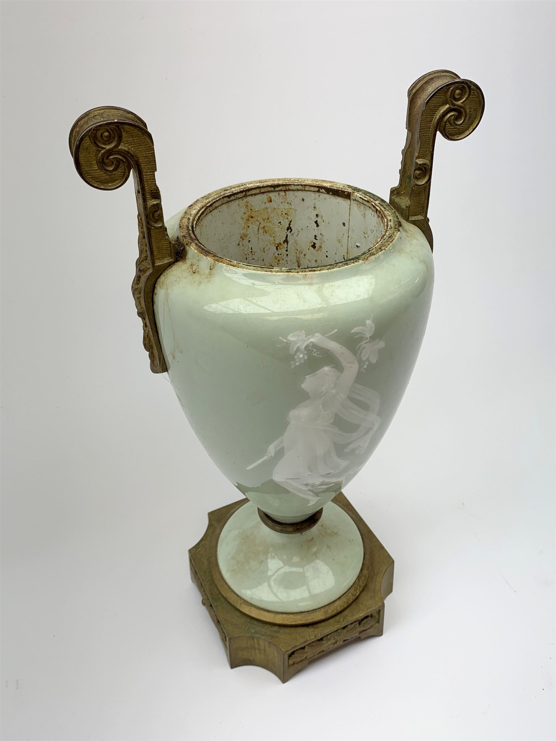 A pate sur pate celadon green vase, of baluster form decorated with a classical female figure to one side, and floral swag with ribbon and musical trophy to the other, with twin gilded scroll handles, and raised upon a gilded base, overall H38.5cm. 