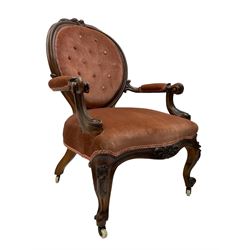 Victorian walnut framed open armchair, cresting rail decorated with cared roses and folate, back and sprung seat upholstered in buttoned coral rose fabric, scrolled arm terminals, raised on cabriole supports with ceramic castors