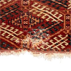 Persian Bokhara crimson ground rug, the field decorated with five rows of repeating Gul motifs with interspersed geometric design, enclosed by a guard band of further geometric-style Gul designs comprised of hook motifs