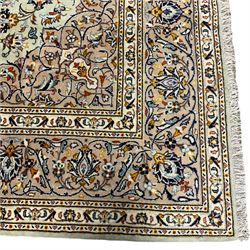 Persian Kashan carpet, light ground and decorated with interlacing branch  and stylised flower head motifs, repeating border