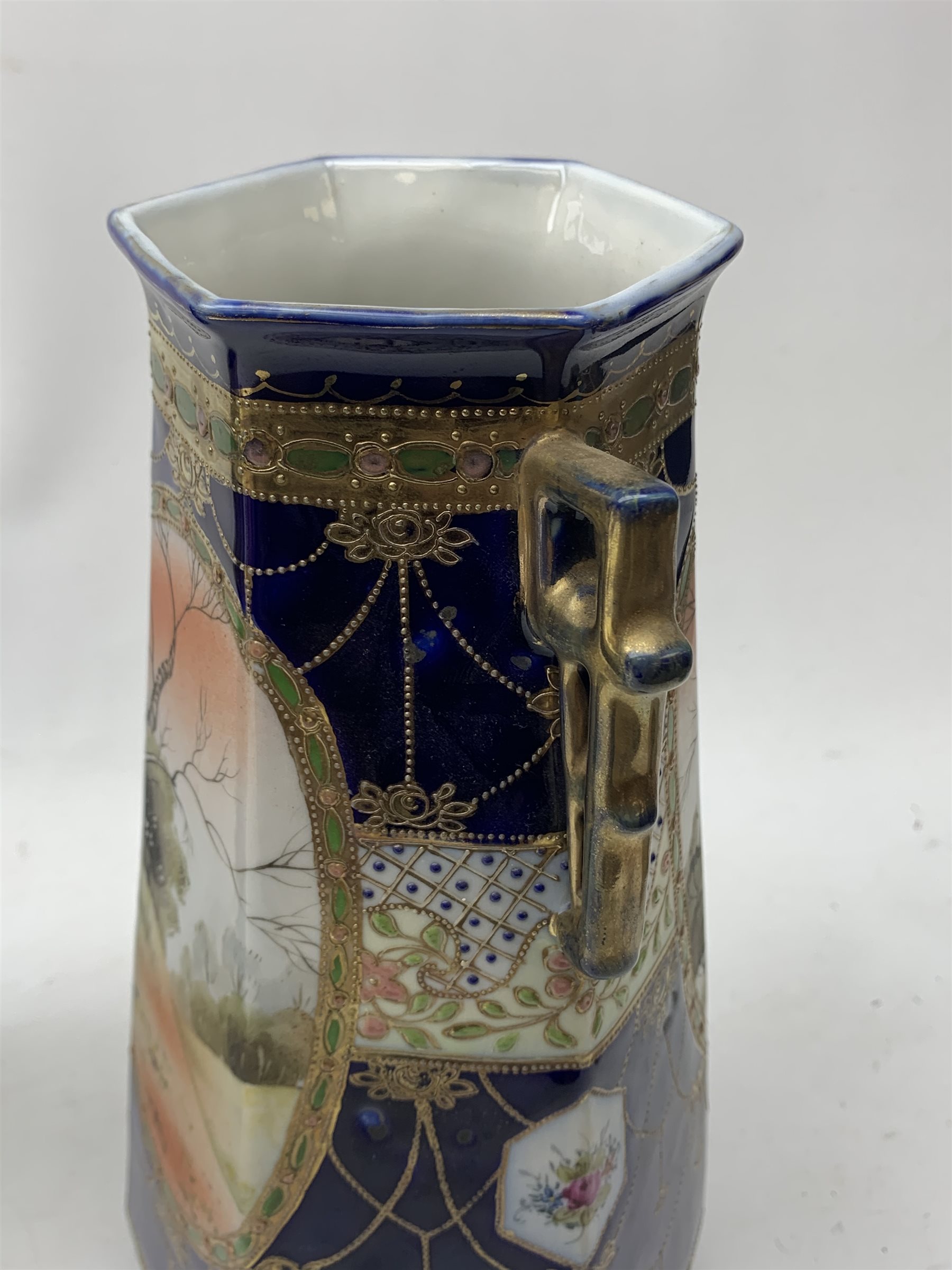 A pair of Japanese Nippon Kinjo vases, of tapering hexagonal form with twin stylised handles, the cobalt blue ground with oval hand painted panels to front and verso depicting landscapes, further detailed with smaller floral bands and panels and heightened with gilt, each with mark beneath, H30.5cm.  